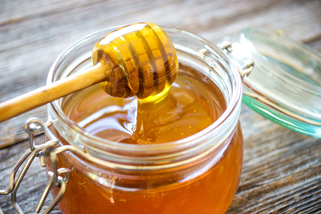 pot de miel bio avec une cuillère coulant de miel pure 